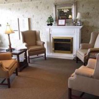 A cozy living room with armchairs arranged around a fireplace.