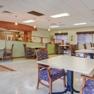 An empty cafeteria with neatly arranged tables and chairs, illuminated by overhead lighting.