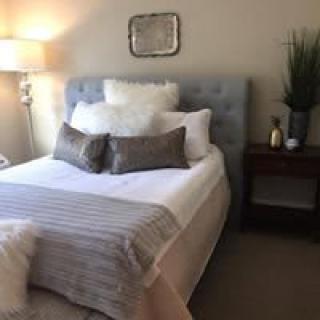 A cozy bedroom with a neatly made bed, stylish pillows, and a modern lamp on the nightstand.