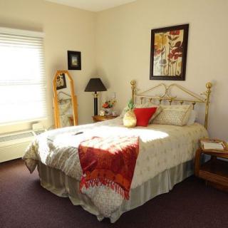 A cozy bedroom with a neatly made bed, decorative pillows, and artwork on the wall.