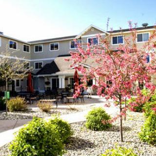A charming residential building surrounded by beautiful landscaping and blooming flowers.