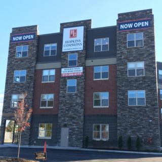 A modern hotel building featuring stone and brick facade with 'Now Open' signs.