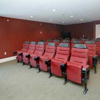 A home theater with rows of red reclining seats.