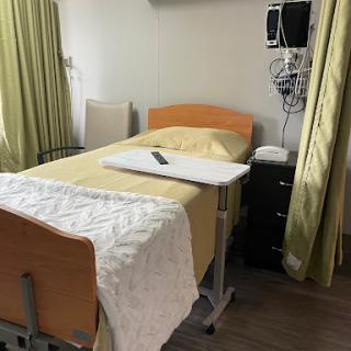 A patient room in a hospital, featuring a bed, medical equipment, and curtains for privacy.