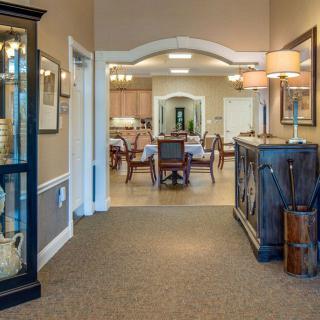 A hallway leading to a cozy dining area, adorned with elegant furniture and warm lighting.