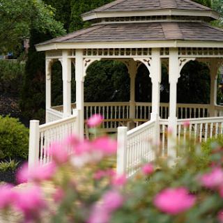 A charming gazebo surrounded by vibrant flowers in a serene garden setting.