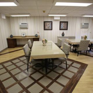A well-arranged dining room with a large table and chairs on a patterned carpet.