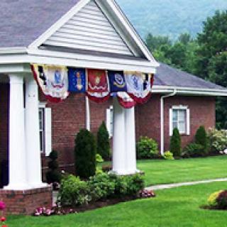 A beautifully landscaped house adorned with patriotic banners, welcoming guests with its charming front porch.