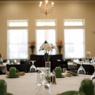 An elegantly set dining table with a central floral arrangement and soft natural lighting.