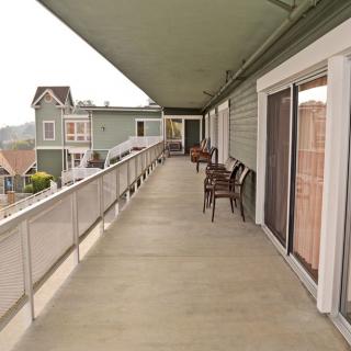 A long outdoor corridor with seating at an apartment building.