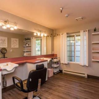 A cozy hair salon with a stylish interior featuring a large mirror, comfortable salon chair, and warm lighting.