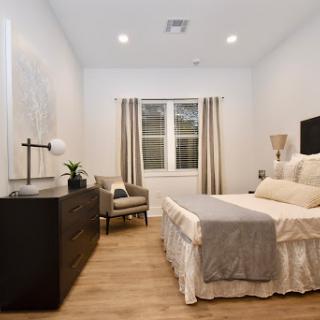 A modern and cozy bedroom featuring a neatly made bed, stylish furniture, and natural light filtering through the curtains.