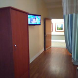 A hospital hallway with a television, curtain, and wardrobe.