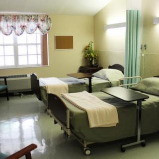 An empty hospital room with neatly arranged beds and curtains.