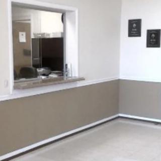 A minimalist waiting area featuring a reception window and neutral-toned walls.