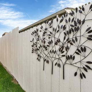 A white fence featuring decorative metal art with a leaf design.
