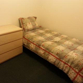 A minimalist bedroom with a single bed and a small dresser.