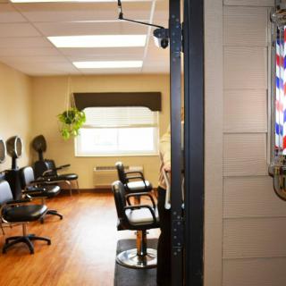 A neat and organized barber shop interior with chairs and a classic barber pole at the entrance.