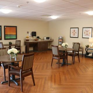 A cozy dining area with wooden tables and chairs, decorated with flowers and artwork on the walls.