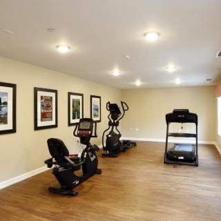 A home gym featuring a treadmill, stationary bike, and elliptical machine in a spacious room.