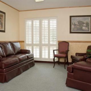 A cozy living room with leather sofas, chairs, and framed artwork on the walls.