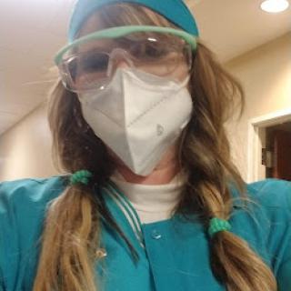 A healthcare professional wearing personal protective equipment (PPE), including a face mask and safety glasses, ready for work.