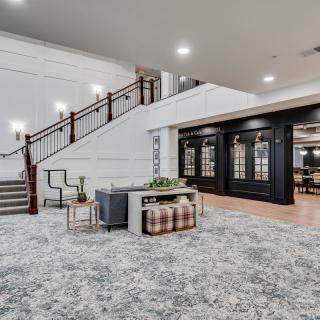 A modern lobby interior featuring a staircase with wooden handrails, stylish carpeting, and contemporary furniture.