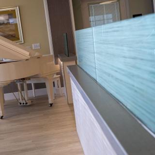 A modern living room featuring a grand piano and a glass partition.