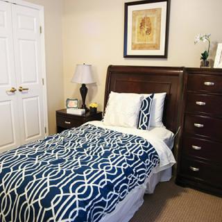 A neatly arranged bedroom with a single bed, nightstand, and dresser.
