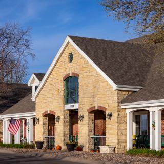 A stone facade house with a gabled roof and columns, featuring an American flag.