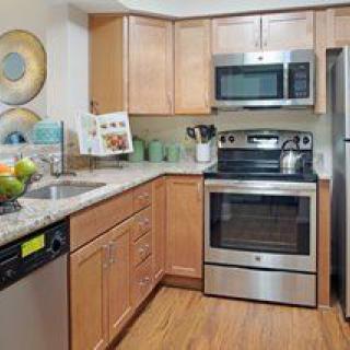 A modern kitchen featuring stainless steel appliances and wood cabinets.