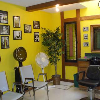 A vintage-themed hair salon interior with yellow walls, wall art, and seating.