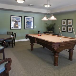 A cozy game room featuring a pool table, classic furniture, and elegant wall art.