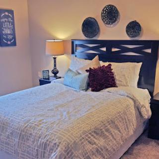 A cozy and well-decorated bedroom featuring a neatly made bed, decorative pillows, and stylish wall art.