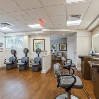 A modern hair salon interior with styling chairs and mirrors on a wood floor.
