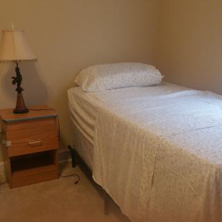 A simple bedroom with a single bed and nightstand.