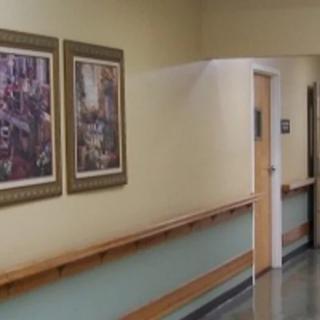 A hallway with artwork on the walls, a wooden handrail, and a closed door.