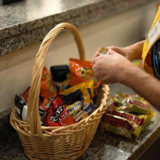 A person is selecting snacks from a woven basket on a granite countertop.