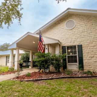A charming stone-front house with a welcoming porch and American flag.
