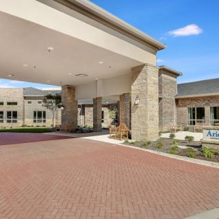 A modern building entrance with a covered driveway and stone pillars.