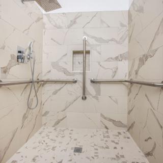 Modern bathroom shower with marble walls and accessible features.