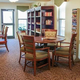 A cozy library room with a table and chairs surrounded by bookshelves.