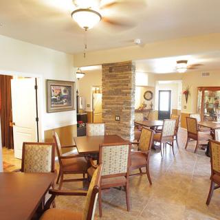 A spacious dining area featuring multiple tables and chairs, complemented by modern decor and ceiling fans.
