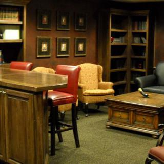 A cozy office space featuring comfortable chairs, a wooden desk, and bookshelves.