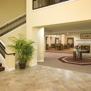 A spacious lobby area featuring a staircase, potted plant, and comfortable seating.
