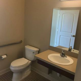 A clean and simple bathroom with a sink, mirror, and toilet.