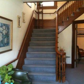 A traditional-style staircase with wooden railings, adorned with framed artwork and greenery.