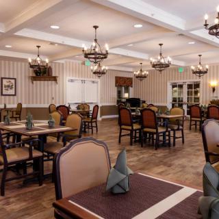 An elegant dining room with neatly arranged tables and chandeliers.