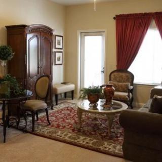 A traditionally styled living room with elegant furniture, a patterned carpet, and red curtains.