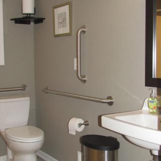 A bathroom with accessibility features, including grab bars next to the toilet and sink.